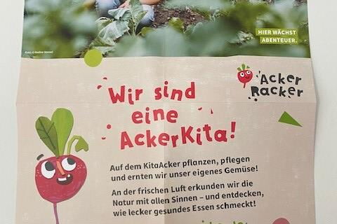 Plakat: Bild Zwei Kinder in einem Beet. Text: Wir sind eine AckerKita! Auf dem KitaAcker pflanzen, pflegen und ernten wir unser eigenes Gemüse. An der frischen Luft erkunden wir die Natur mit allen Sinnes und entdecken wie lecker gesundes Essen schmeckt!
