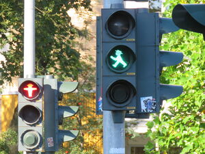 2 Fußgängerampeln, die hintere auf rot, die fordere auf grün. Ampelmännchen.