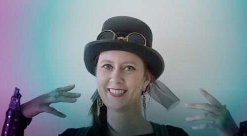 Frau mit im Steampunk Style. Kopf und, Hals und Hände sind sichtbar. Sie trägt Steampunk Hut und Ohrringe. Sie ist geschminkt.
