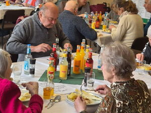 Menschen an Tischen beim Essen, es gibt Spargel und Getränke stehen auf den Tischen. Gemeinsames Mittag.