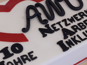 Eine Tort mit der Zuckerguss Aufschrift: "10 Jahren AWO Netzwerk Arbeit Inklusiv" steht auf einem Tisch