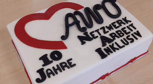 Eine Tort mit der Zuckerguss Aufschrift: "10 Jahren AWO Netzwerk Arbeit Inklusiv" steht auf einem Tisch