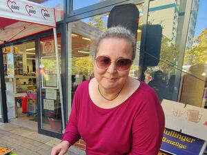 Kuchenbasar. Frau mit Sonnenbrille gibt ein Kuchenstück einer Besucherin.