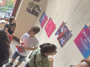 Ein helles Treppenhaus, Menschen auf den Stufen. An den Wänden hängen Ausstellungstafeln.