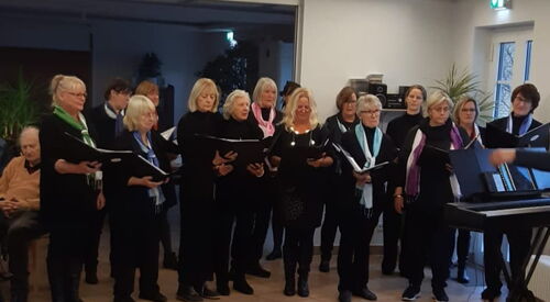 Innenraum. Frauen in schwarzer Kleidung mit Gesangsbüchern in den Händen.