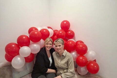 Sofa, darauf sitzend stellvertretende Pflegedienstleitung Jennifer Döppner und Pflegedienstleitung Kathleen Busse, im Hintergrund viele rote und weiße Ballons