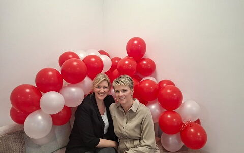 Sofa, darauf sitzend stellvertretende Pflegedienstleitung Jennifer Döppner und Pflegedienstleitung Kathleen Busse, im Hintergrund viele rote und weiße Ballons