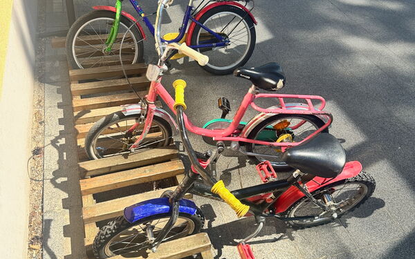 Eine halbierte Europalette dient als Kinderfahrradständer. 3 Räder sind geparkt.