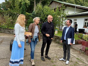 2 Frauen und 2 Männer draußen. Rechts im Hintergrund ein weißes Haus.