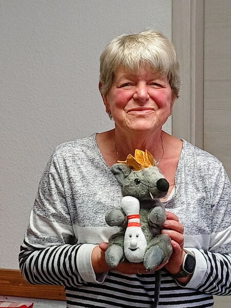 Frau hält Plüsch-Rattenkönig vor sich und lächelt.