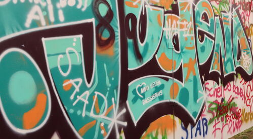 Eine Mauer / Wand, voll gesprayt mit Worten. Das grüößte ist das Wort Jugend - darin das AWO Logo - AWO gegen Rassismus.
