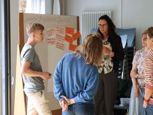 Jungendorte steht am Flipchart um den sich eine kleine Arbeitsgruppe gebildet hat.