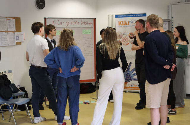 Kleingruppe steht um Flipchart zum Thema Kinder und Jugendgerechte Beteiligung.