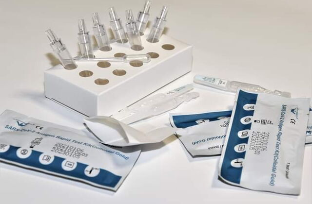 Drei verpackte Corona Tests. Ampullen in einem Pappständer