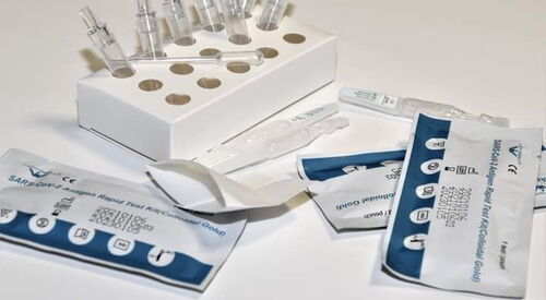 Drei verpackte Corona Tests. Ampullen in einem Pappständer