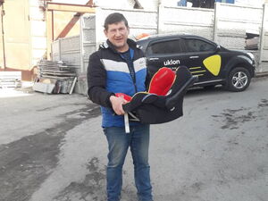 Ein Mann vor einem Auto mit einem Kindersitz in der Hand