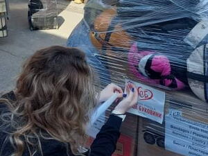 Eine Frau klebt Zettel an eine Palette mit Spendenkartons