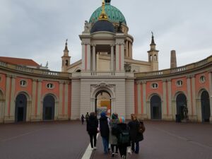 Innenhof des Landtag Brandenburg. Eine kleine Gruppe von Menschen geht zum Portal. Im Hintergrund die Kuppel der Nikolaikirche.