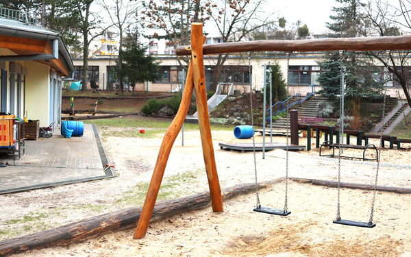 Spielplatz einer Kita. Zwei Schaukeln, weiter hinten eine Rutsche.