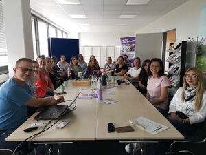 Gruppenbild im Konferenzraum. Viele Personen sitzen um einen Tisch und lächeln in die Kamera.