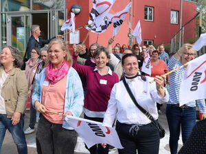 Teilnehmende mit weißen AWO Flaggen gehen fröhlich voran.