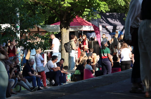 Menschen bei einer Open Air Veranstaltung unter Bäumen.