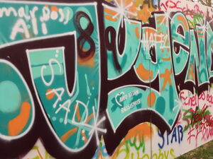 Eine Mauer / Wand, voll gesprayt mit Worten. Das grüößte ist das Wort Jugend - darin das AWO Logo - AWO gegen Rassismus.