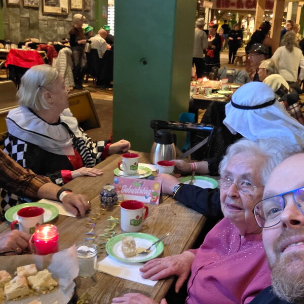 5 Personen an einem Tisch mit Kaffee und Kuchen in einem rustikal eingerichteten Café / Restaurant.