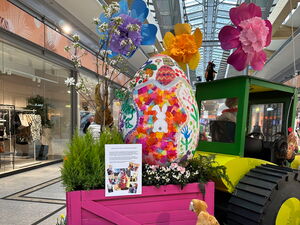 Im Sterncenter. Osterdekoration im Gang. Trecker mit Anhänger. Im Anhänger großes Osterei. Blumen und der Osterhase.