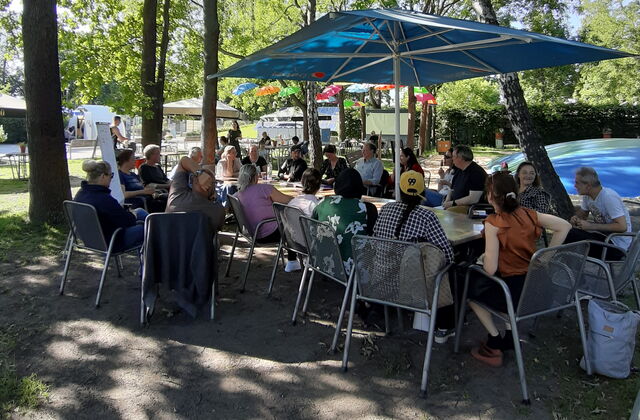 das Foto zeigt eine Gruppe von Menschen, die ein Meeting im Freien abhalten
