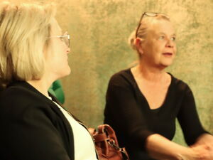 2 Frauen sitzen in grünen Kinosesseln.