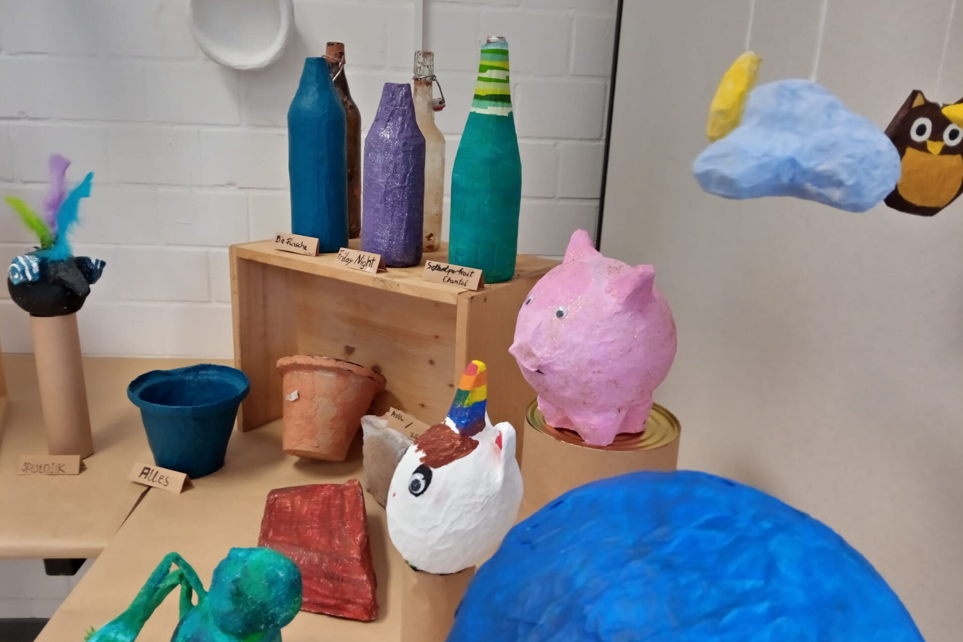Pappmaschee Figuren, Ein rosa Schwein, weißes Einhorn mit Regenbogen-farben Horn, Blumentöpfe