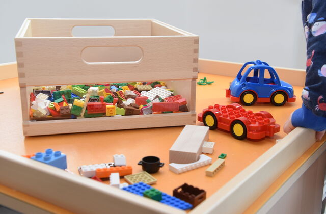 Spieletisch mit Legokiste und kleines blaues Auto.