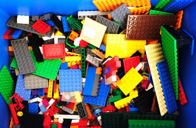 Blick in eine blaue Kiste gefüllt mit Lego-Bausteinen.