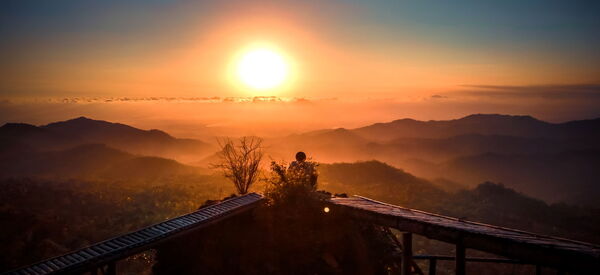 Ein Sonnenuntergang vor hügeliger Landschaft, warme friedliche Atmosphäre