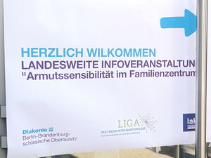 Ein Schild an einer Glastür mit Pfeil. Schild: Landesweite Infoveranstaltung "Armutssensibilität im Familienzentrum"