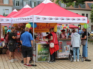 Rote AWO Pavillons: gelbes Banner: "AWO erleben"   Menschen am Stand  die sich informieren.