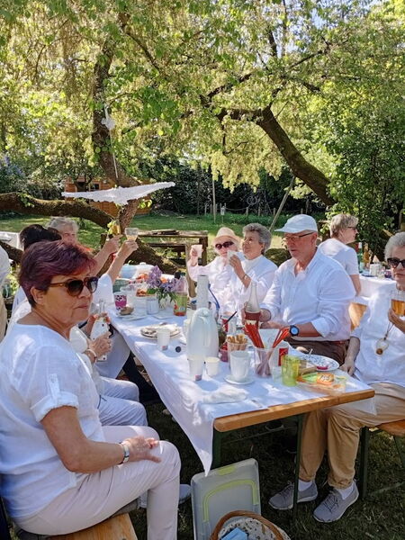 Menschen in weißer Kleidung an einem gedeckten Picknicktisch.