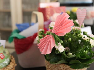 Geschenkkörbchen und im Vordergrund eine Blühpflanze mit Deko.