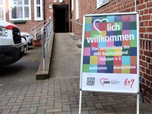 Eine Rampe führt zu einer offenen Tür. Davor ein Schild der AWO: Herzlich willkommen - Eine Veranstaltung des AWO Bezirksverband Potsdam e.V.