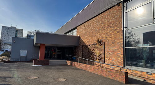 Rechts Schwimmhalle mit Rampe zum Eingang.