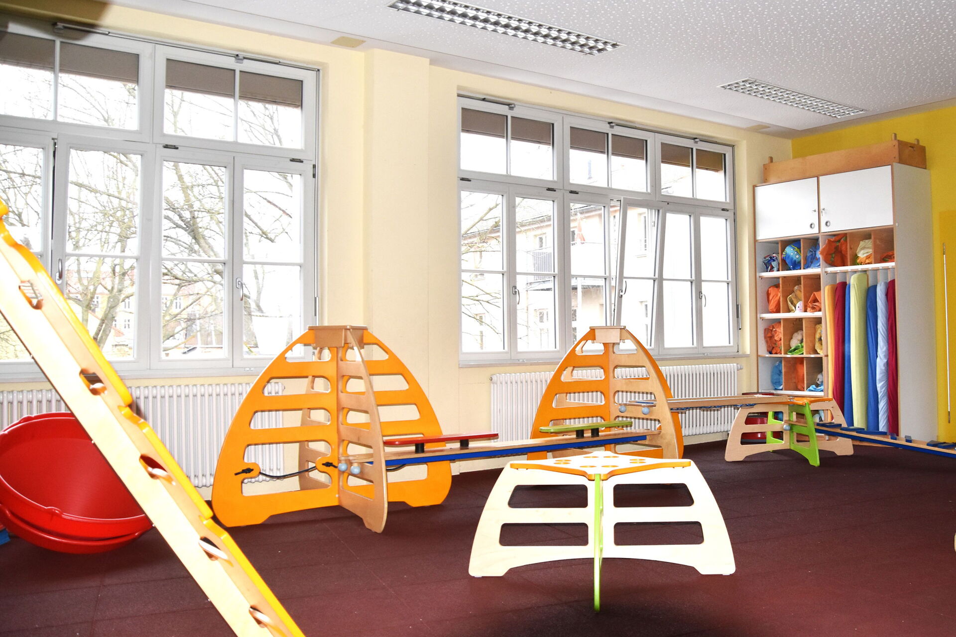 Großer Raum mit vielen Fenstern die Licht rein lassen. Im Raum Kletter- und Balance Sportgeräte.