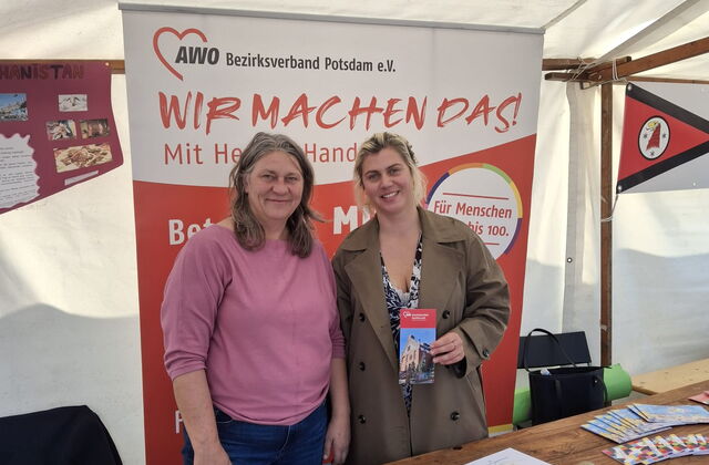 das Bild zeigt zwei Mitarbeiterinnen des interkulturellen Familiencafés , wie sie an einem Stand der AWO stehen und Flyer präsentieren