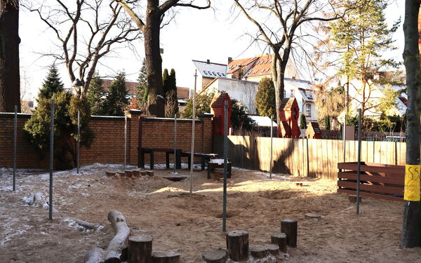 Es ist Winter. Raureif und etwas Schnee auf dem Spielplatz der Kita. In der hinteren Ecke des eingezäunten Geländes ist ein Wasserspeilplatz.