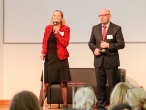 Dörte Maack, Autorin und Moderatorin, steht mit Blindenstock auf der Bühne und moderiert den Vortrag eines Potsdamer Unternehmers an.