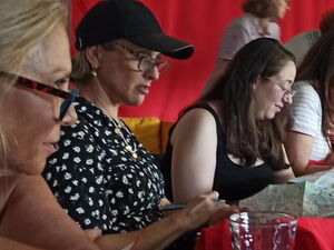 Frauen sitzen an einem Tisch. Auf dem Tisch: Gläser, Wasserflaschen, Stadtpläne.