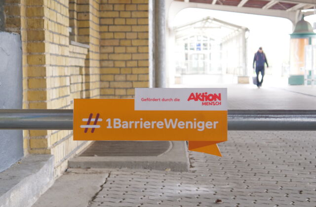 Auf einem Schild steht der Hashtag Eine Barriere weniger