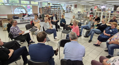 Ein großer Raum, 21 Menschen sitzen in Stuhlkreisen. In der Mitte wird diskutiert.