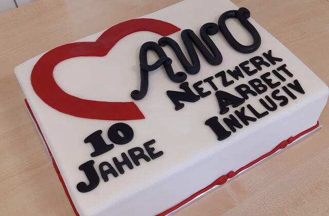 Eine Tort mit der Zuckerguss Aufschrift: "10 Jahren AWO Netzwerk Arbeit Inklusiv" steht auf einem Tisch