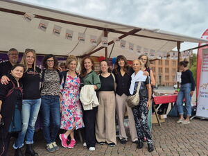 Gruppenfoto: 10 Personen vor einem Aktionsstand des AWO Büro Kinderarmut. Der Stand hat eine Zeltplane oben und hinten. Rollups und Plakatständer zu beiden Seiten.